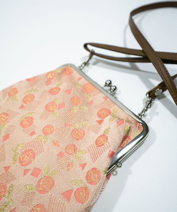 Floral patterned handbag with a metal frame on a white background