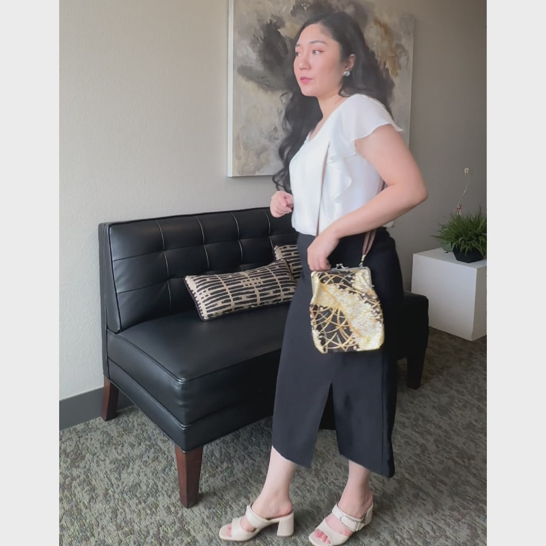Night Sakura kinran fabric shoulder gamaguchi bag with black and gold floral pattern shown in motion